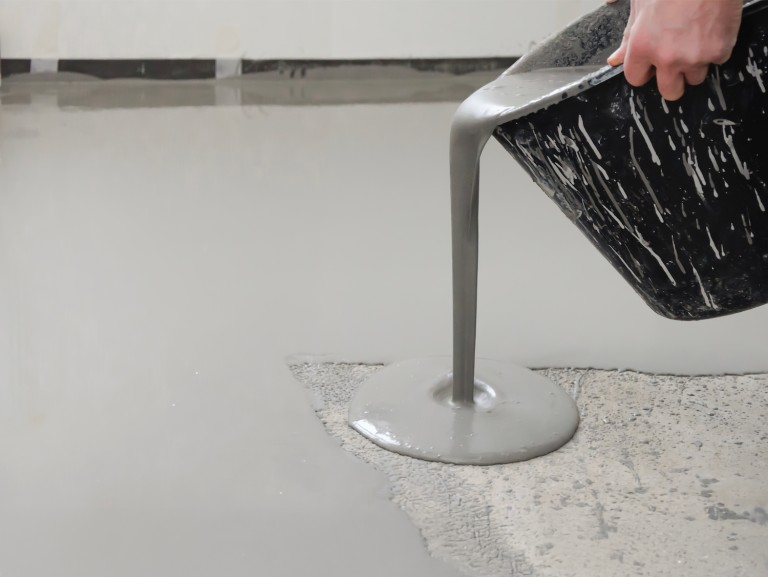 Pouring self-leveling cement compound on concrete base for interior floor leveling