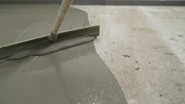 Self-leveling cement slurry flowing evenly to create a smooth floor base